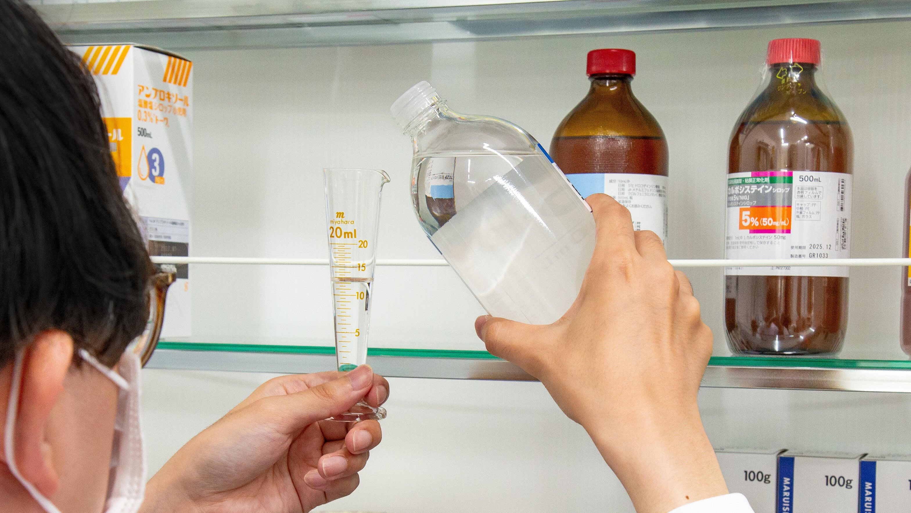 薬剤師が計量容器へ水剤を入れている様子の写真。