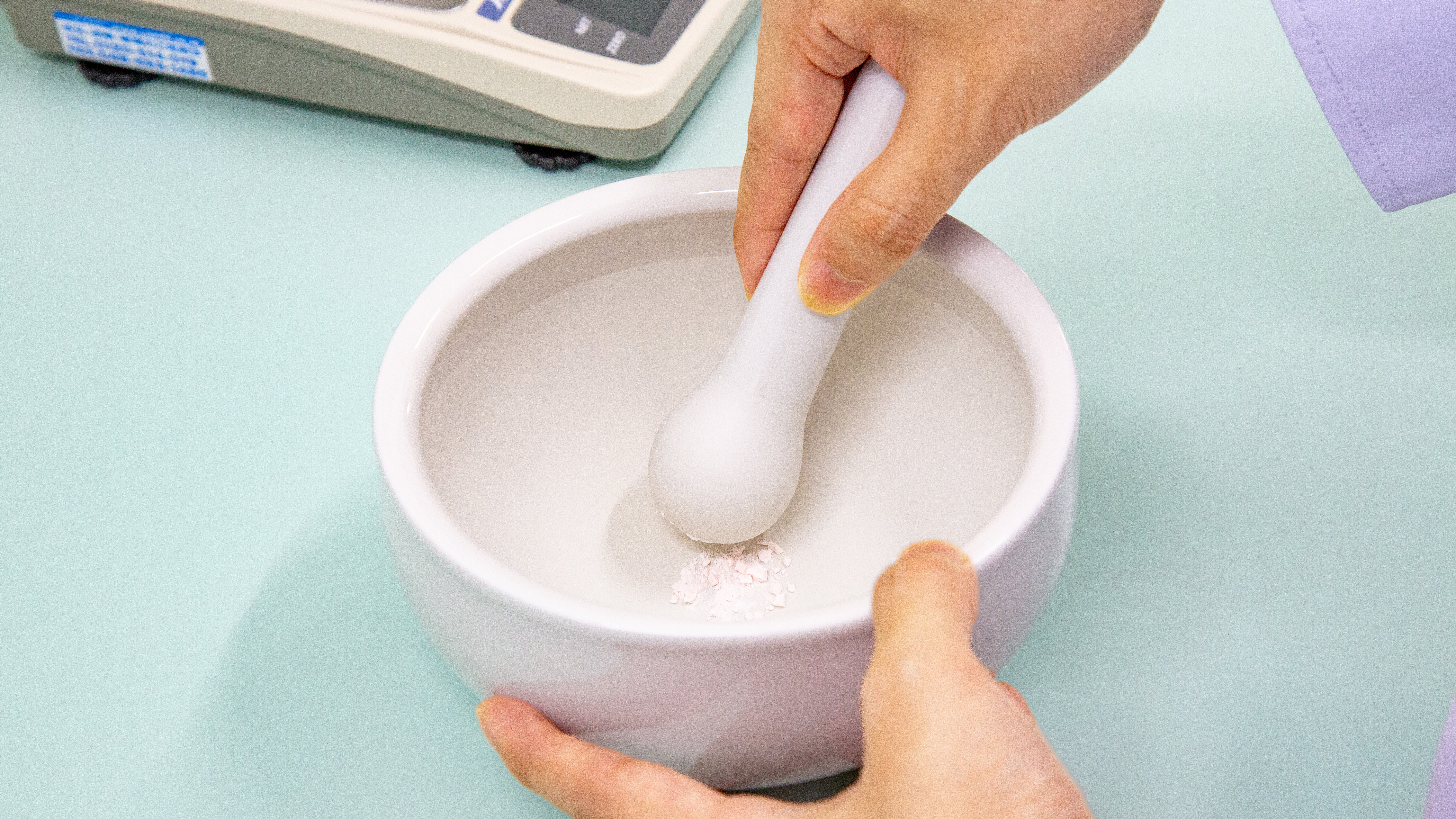 乳鉢と乳棒を使って錠剤を砕いている様子の写真。
